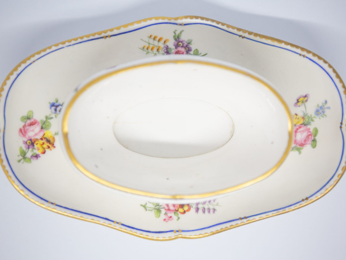 18th Century Sevres sauce boat. Soft paste porcelain sauce boat hand-painted in the feuille de choux pattern. Hairline crack to the inside of the sauce boat which does not come through under the plate. Interlaced L mark of Sevres to the base with double letter a denoting 1778. Photo looking straight down at sauce boat with lid removed and shown directly from above
