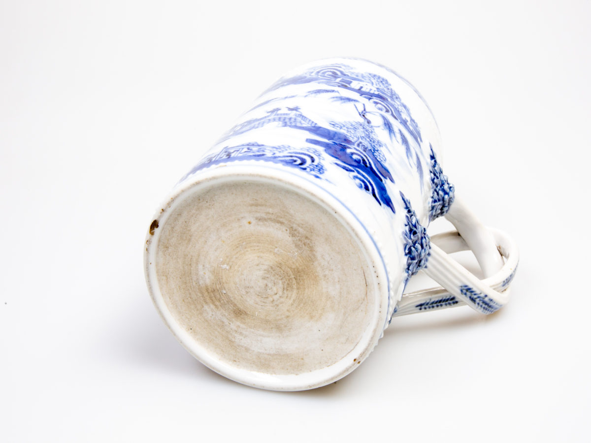 Antique Chinese blue and white tall mug. Rare mug from the Qianlong Li era c1736-1795. Decorated in classic willow pattern with an intricate and unusual 2 pleat handle. Small chip of the paint on the outer pleat handle and what appears to be a crack but most likely a consequence of the manufacturing process on the top of the inner pleat handle.  Otherwise in excellent condition for its age. Measures 82mm in diameter at base, 72mm across the top and 130mm at widest. Photo of base of mug