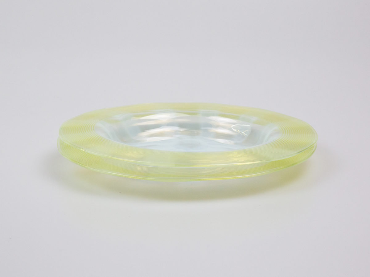 Pair of Art Deco glass side dishes. Handmade small shallow dishes with an unusual colour pattern of pale blue star burst to the centre and yellow green rim. Some minor signs of wear. Each dish measures approximately 100mm in diameter at base, 165mm across the top and 15mm in depth. Photo of both dishes on top of each other and seen from a near eye level showing the depth