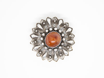 Egyptian silver brooch set with a carnelian to the centre. Intricate design of filigree work integrated with silver globules. Hallmarked to the pin. Measures 45mm in diameter. Main photo of brooch front