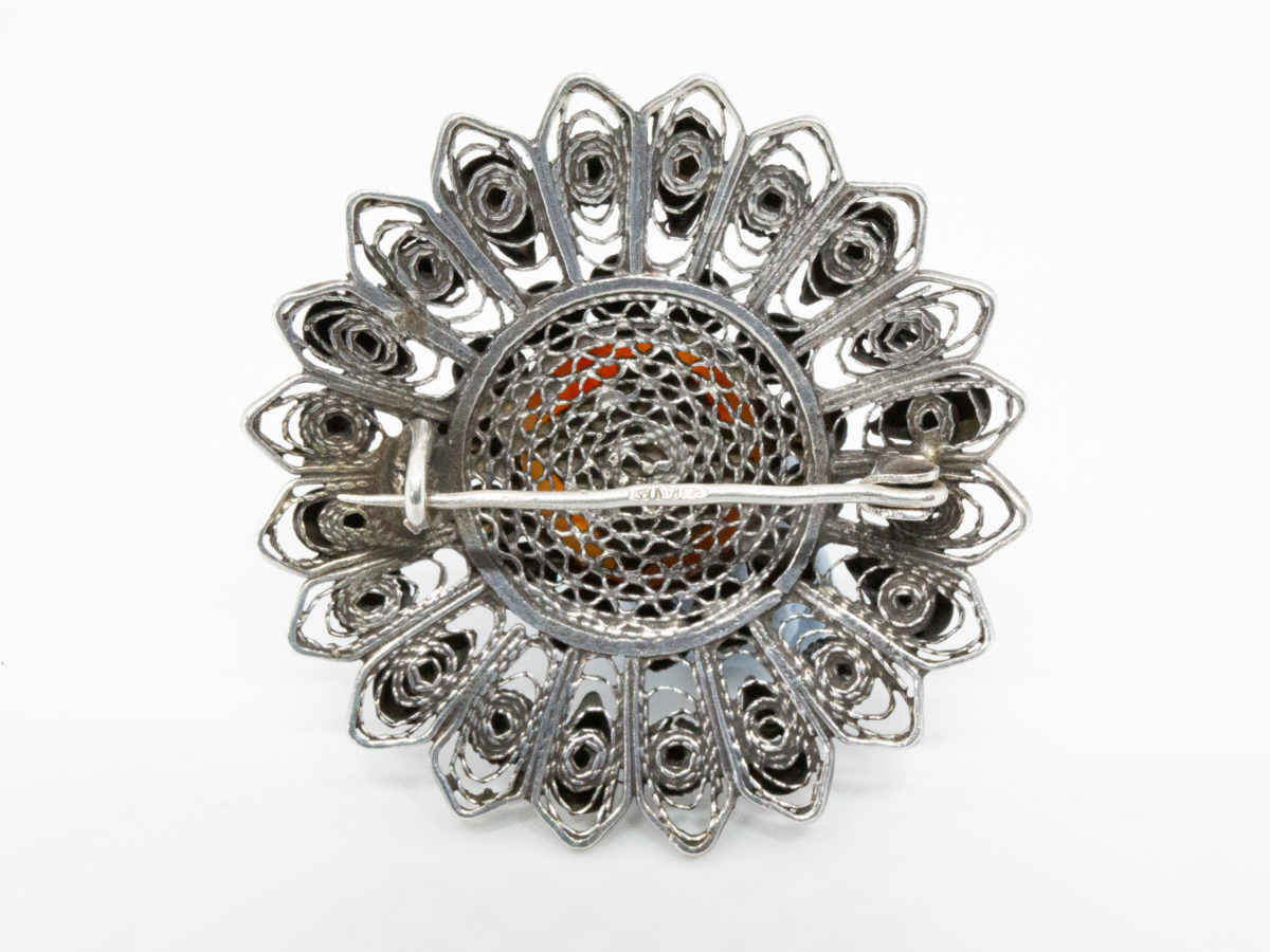 Egyptian silver brooch set with a carnelian to the centre. Intricate design of filigree work integrated with silver globules. Hallmarked to the pin. Measures 45mm in diameter. Photo of back of brooch
