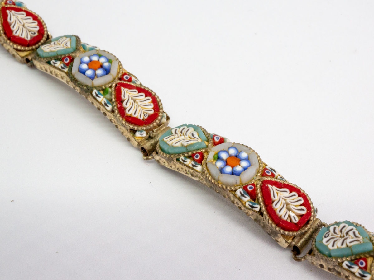 Vintage Italian micro mosaic bracelet. 5 panel white metal bracelet inlaid with micro mosaic beads in a pretty floral design. In very good order throughout with only 1 small bead missing. Close up photo of a couple of panels
