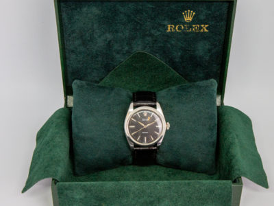 Rolex Oyster stainless steel watch. Vintage Rolex Oyster Precision watch with an almost new black leather strap. Buckle and leather strap are not original. Watch face measures approximately 30mm in diameter. Strap is adjustable from 155mm to 195mm. Watch weighs 42.8gms. Comes in green Rolex box. Some signs of wear to the glass. VIEWING IN STORE BY APPOINTMENT ONLY. Main photo of Rolex watch displayed inside open forest green Rolex case