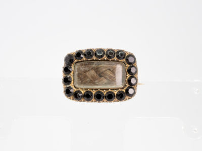 Georgian 9 karat gold mourning brooch. Small rectangular brooch with finely pleated piece of hair to the centre and framed with round cut jet stones. Beautifully inscribed in italics to the back and dated 1823. Stunning piece. Main photo of brooch seen from the front showing the pleated piece of hair within