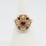 Vintage 9 karat gold ring with garnets and seed pearls. c1959 London assayed 9 karat gold ring with round cut garnet to the centre surrounded by 4 small garnets and seed pearls set on heart shaped petals with leaves on shoulders. Ring size O.5 / 7.75 Ring front measures approximately 18mm by 16mm. Main photo of ring on a display stand shown from the front