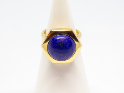 18 karat gold and lapis lazuli ring. Beautiful round lapis stone set on an unusual high hexagonal 18 karat gold mount. Size M.5 / 6.5. Weight 8.1gms. Box included. Main photo of ring displayed on a cone stand seen from the front.