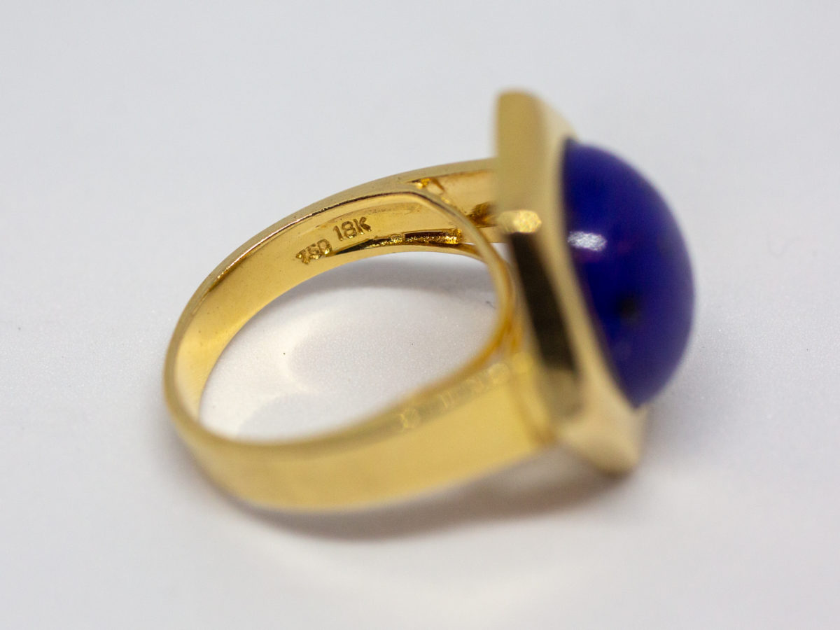 18 karat gold and lapis lazuli ring. Beautiful round lapis stone set on an unusual high hexagonal 18 karat gold mount. Size M.5 / 6.5. Weight 8.1gms. Box included. Close up photo of the hallmark on the inside band