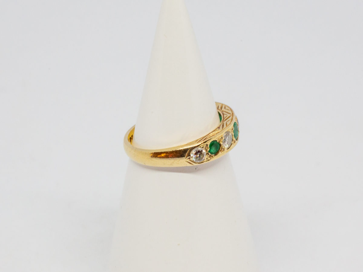 18 Karat gold, emerald and diamond. c1975 London assayed ring set with 5 round cut diamonds and 4 emeralds. Size O.5 / 7.25. Weight 3.8gms. Box included. Photo of ring on a cone display with stones to facing right of picture