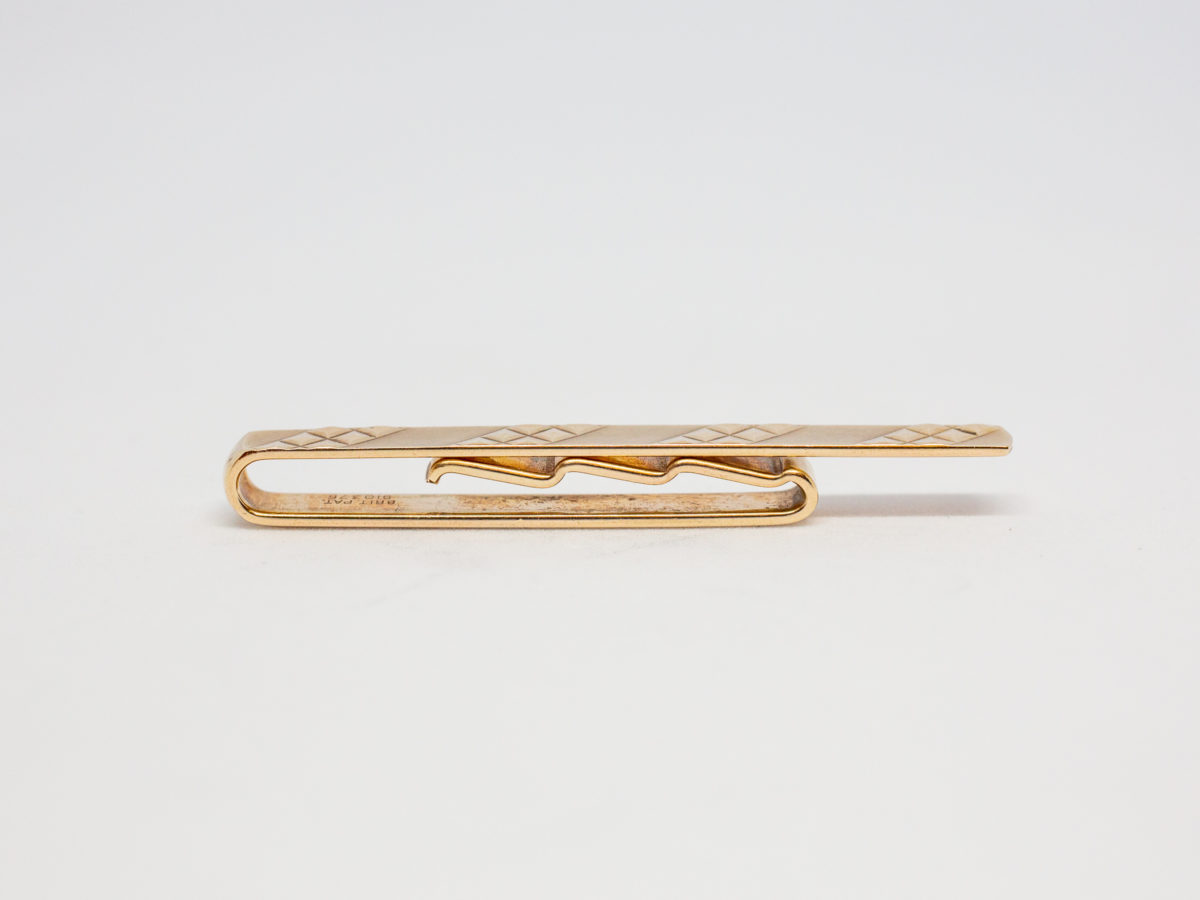 c1991 Solid 9 karat gold tie clip. Very simple yet stylish gents tie clip in solid 9 karat gold. Nice solid fastening. Photo showing the cross section of clip and its fastening mechanism.