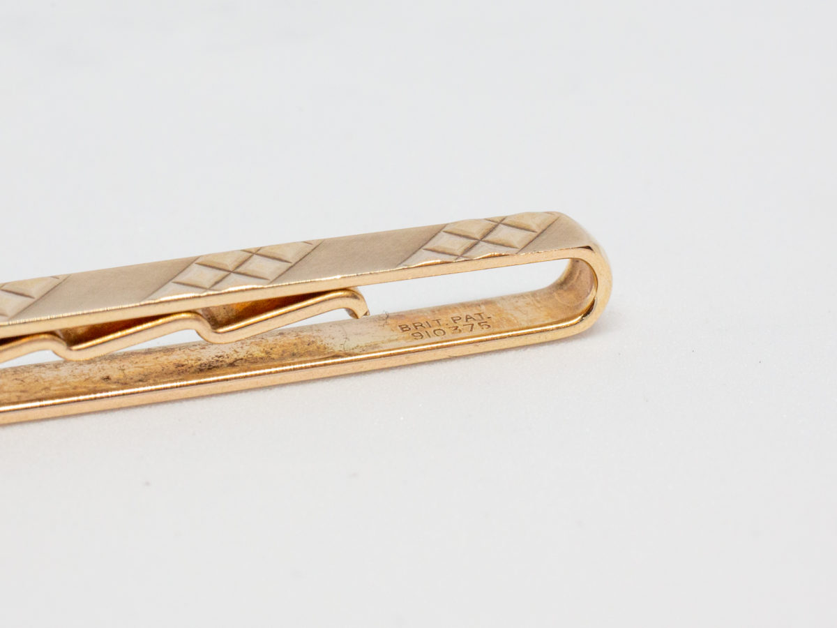 c1991 Solid 9 karat gold tie clip. Very simple yet stylish gents tie clip in solid 9 karat gold. Nice solid fastening. Close up photo of the patent number on the inner band of clip