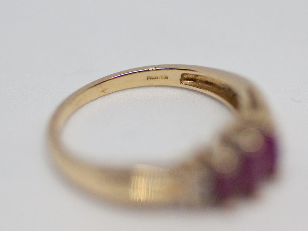 Dainty 9 karat gold and ruby. Sweet and delicate ring set with 3 marquise cut rubies with small round cut diamond to either side. Ring size M / 6.25 Weight 2.4gms. Box included. Close up photo of the hallmark and makers mark on the inside band