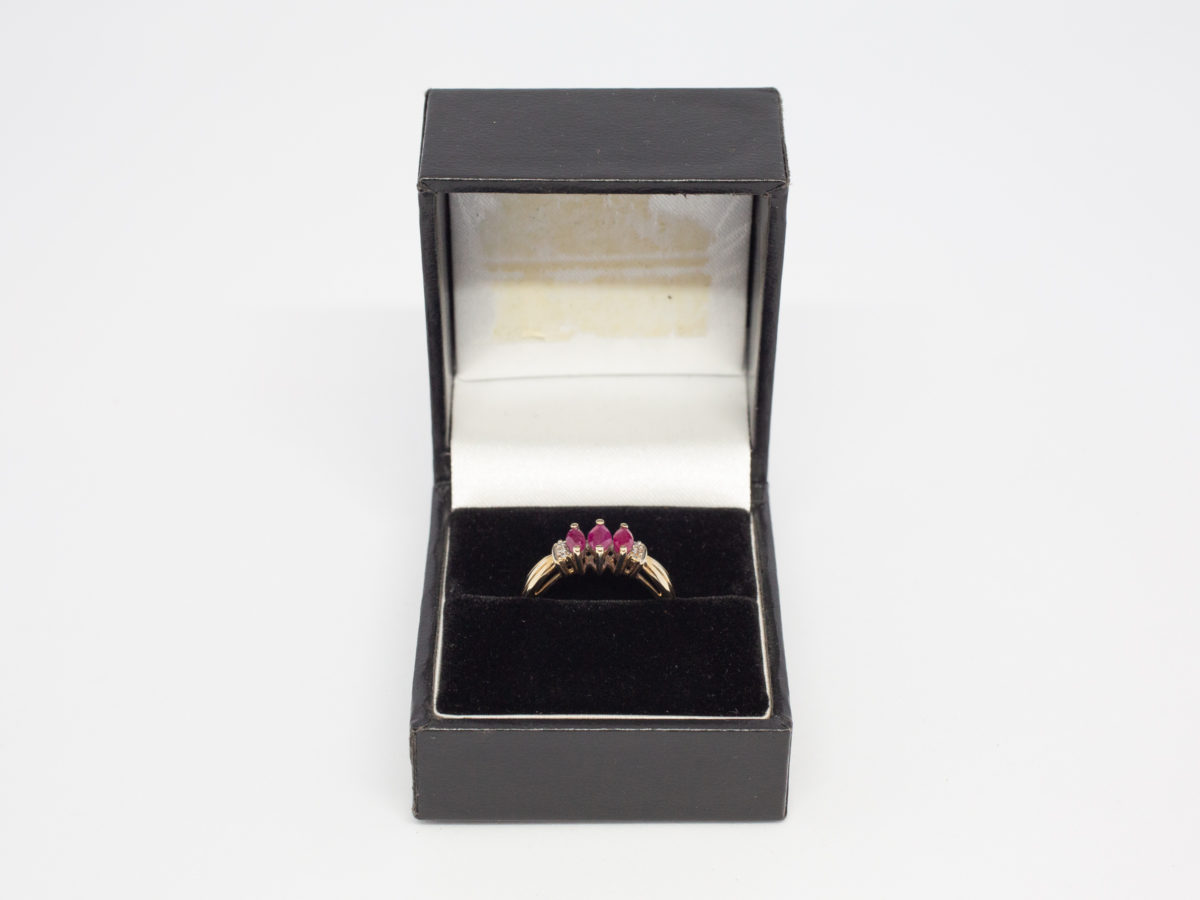 Dainty 9 karat gold and ruby. Sweet and delicate ring set with 3 marquise cut rubies with small round cut diamond to either side. Ring size M / 6.25 Weight 2.4gms. Box included. Photo of ring displayed in box (included)