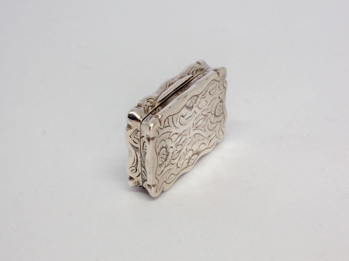 c1872 Victorian sterling silver vinaigrette. A sweet rectangular vinaigrette decorated on both sides with a vacant cartouche for personalisation. A flower decorates the inner grille. Fully hallmarked to the inside lid as well as lower section. Assayed in Birmingham by Frederick Marson. In excellent condition. Photo of vinaigrette on its side with opening side to the top