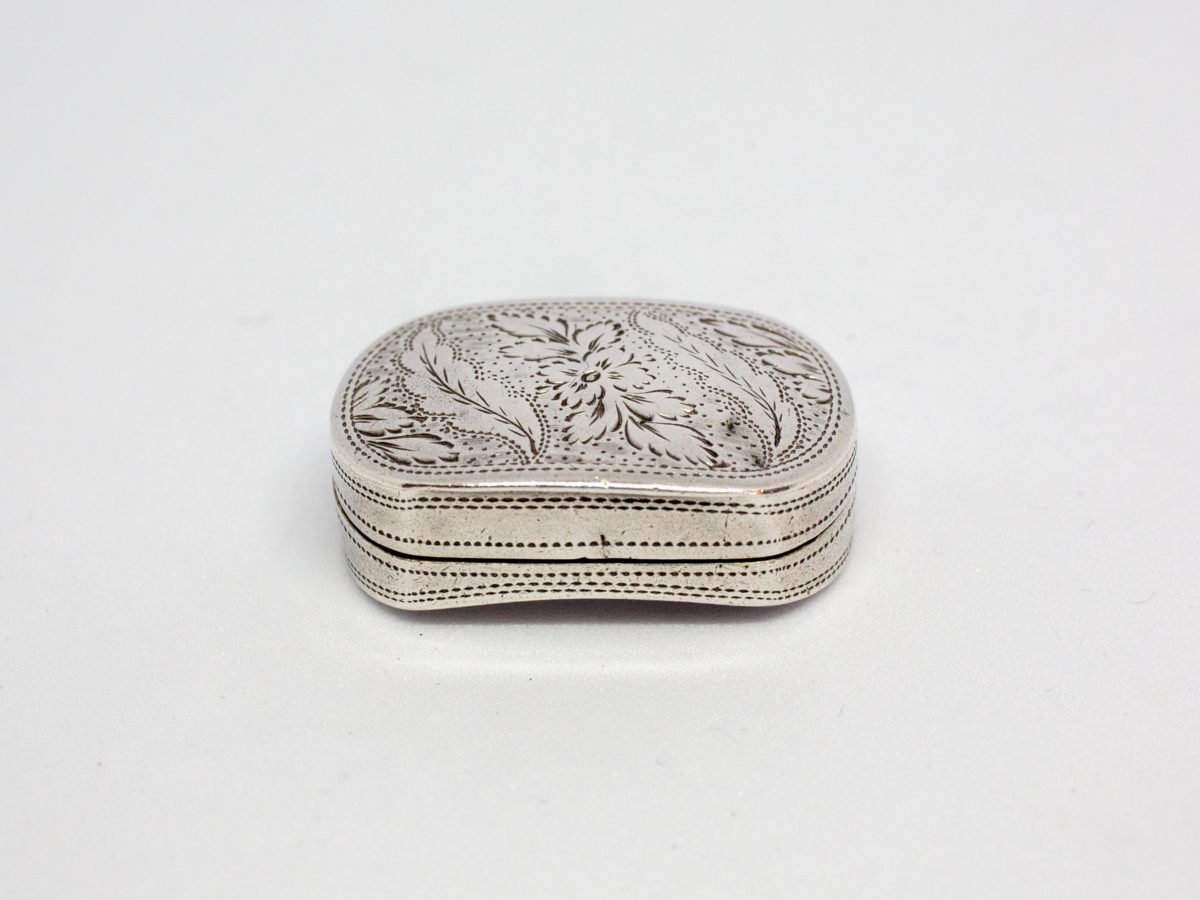 c1807 George III silver vinaigrette. An oblong sterling silver vinaigrette with a curved bottom and a gilt silver interior and grille. Fully hallmarked to the inside of lid for Birmingham assay by silversmith Cocks & Bettridge. A couple of minor dings but closes tight. Main photo of closed vinaigrette scene from the front opening end showing the curve of the base and the pierced silver work design throughout