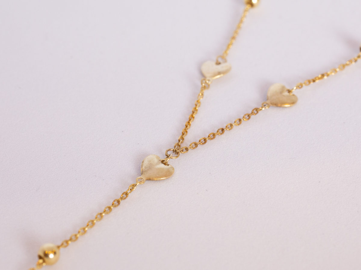 9 karat gold necklace with hearts. Very fine modern 9 karat gold chain embellished with small hearts and baubles and a dangling heart to the end. Measures 410mm long and weighs 1.7gms. Box included. Photo of lower half of necklace showing the hearts to the ends