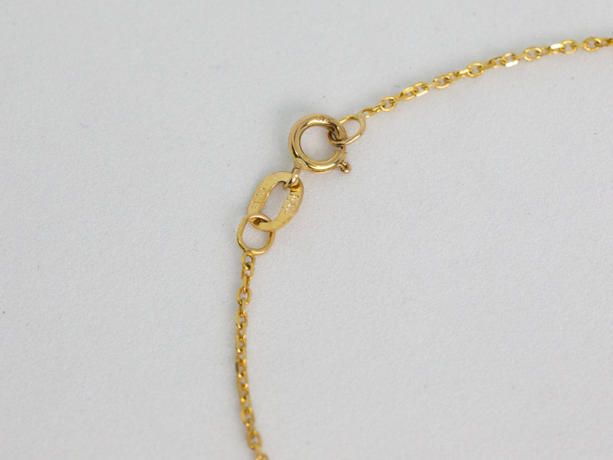 9 karat gold necklace with hearts. Very fine modern 9 karat gold chain embellished with small hearts and baubles and a dangling heart to the end. Measures 410mm long and weighs 1.7gms. Box included. Close up photo of the hallmark on the clasp