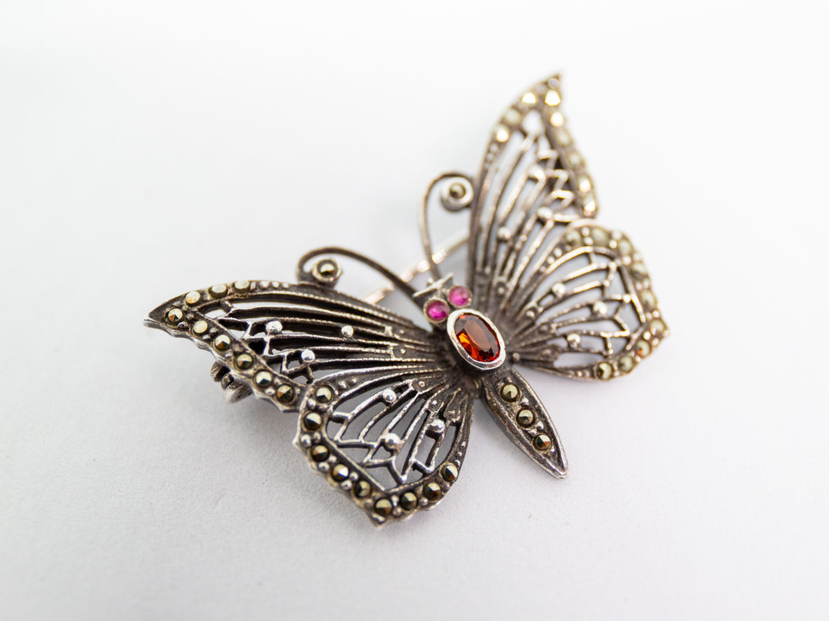Vintage silver and marcasite butterfly brooch. Very pretty brooch with marcasite on wings and abdomen, red glass stone thorax and pink eyes. No visible hallmark. Photo of brooch front shown diagonally