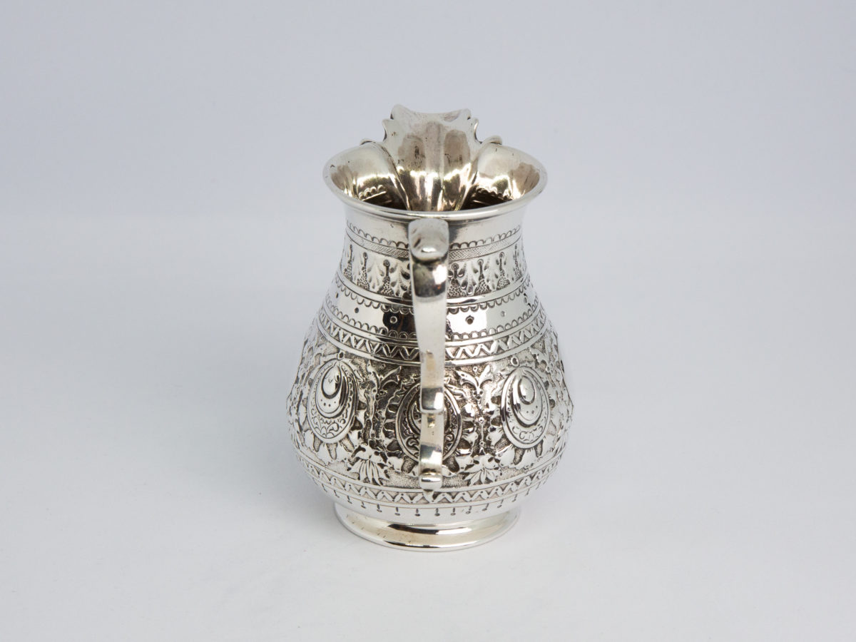c1875 Small sterling silver jug. Very sweet and finely decorated small jug by Barnard & Sons Ltd. Full hallmark to the base for London assay. Stunning piece with empty cartouche to either side for personalisation. Measures 40mm in diameter at the base, 85mm from tip of spout to edge of handle and 45mm across the top. Photo of jug seen from handle end with handle in the foreground