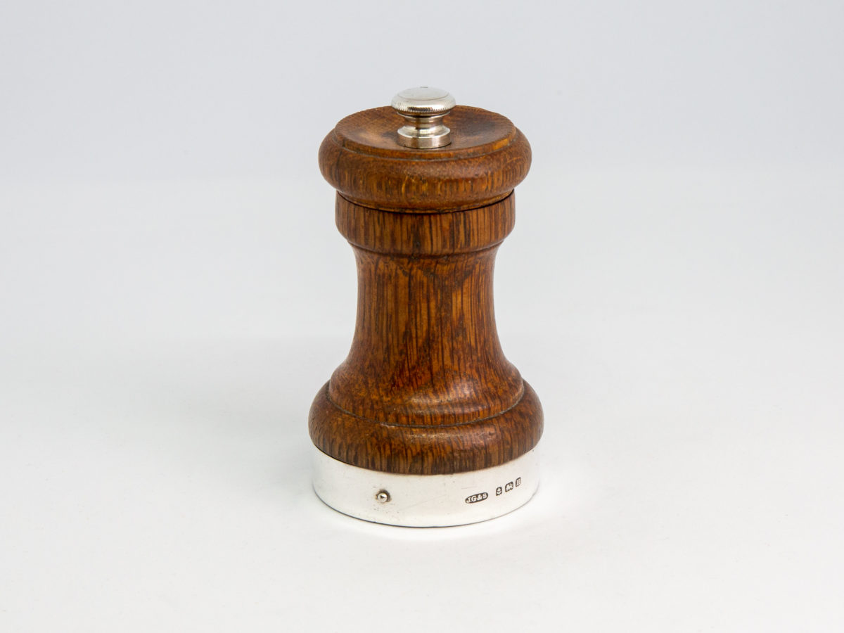 c1932 Small pepper grinder. Petite pepper grinder with oak body and silver top and base rim. The best in pepper grinders with a Peugeot movement. Hallmarked to the base for Birmingham assay and made by John Grinsell & Sons. Lion passant to the top. Measures 45mm in diameter at base and 42mm in diameter at top. Main photo of whole grinder.