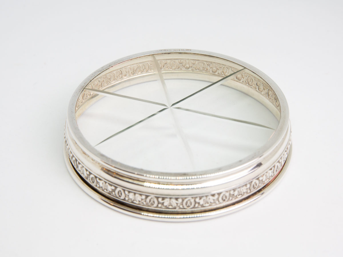 Birks USA silver rimmed glass coaster. Fine quality etched glass coaster with a sterling silver edging. Hallmarked Birks Sterling to the base. Measures 76mm in diameter at base and 82mm across the top. Photo of coaster shown with base end up