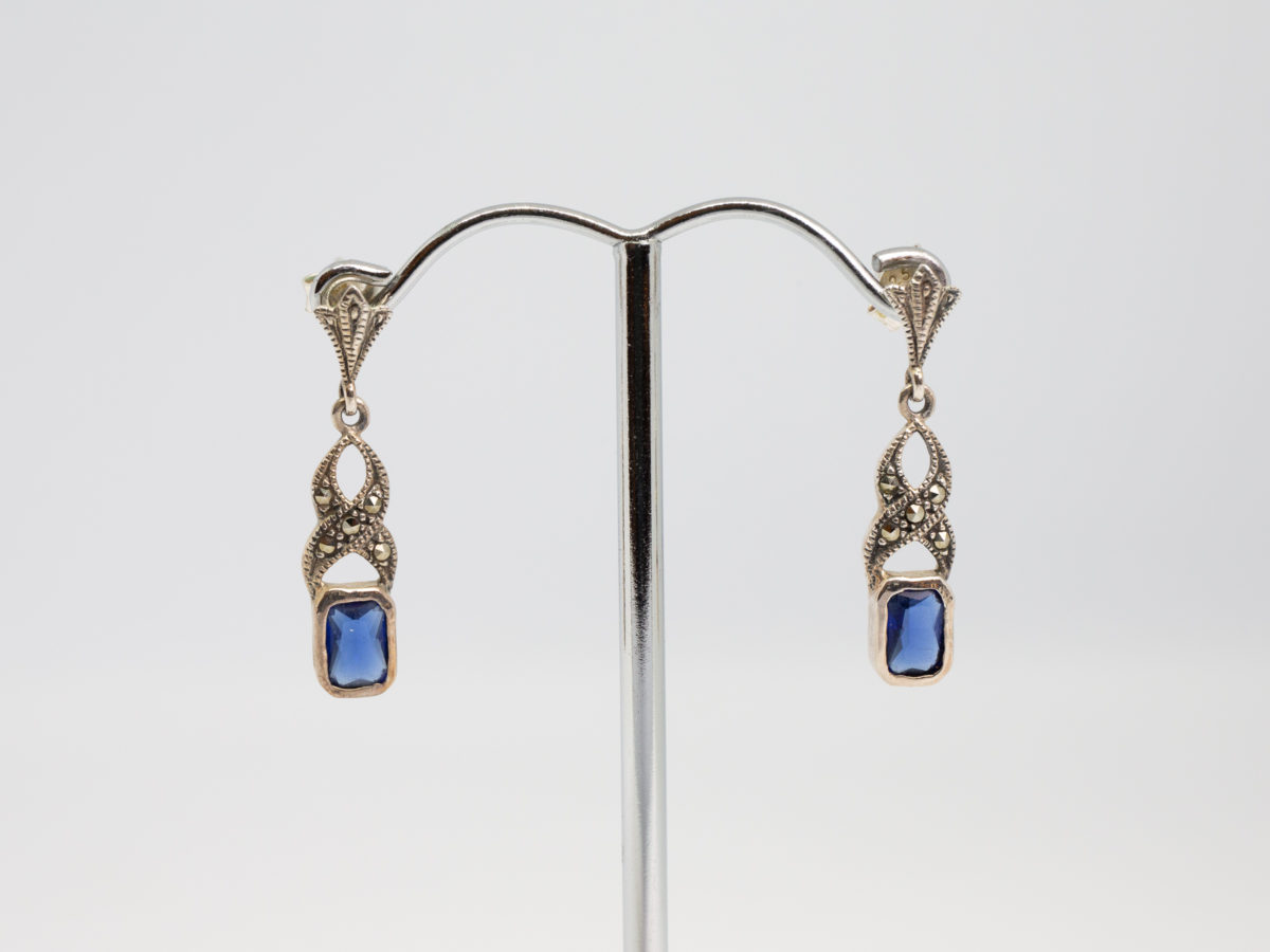 Art Deco style sterling silver earrings. Vintage earrings in a Deco style with marcasite and blue glass detail. Hallmarked 925 for sterling silver to back of earrings and butterfly fasteners. Box included. Earring drop length approximately 30mm. Earrings weight 2.8gms. Main photo of earrings displayed on a stand and shown from the front
