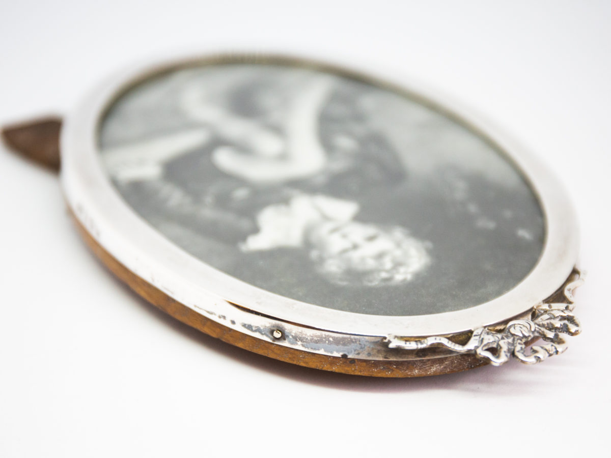 Antique sterling silver oval photo frame. Lovely oval photo frame with pretty ribbon detail to the top. Nice solid wood back. Full hallmark to the side for Birmingham assay c1916. Visible photo area measures 130mm by 88mm at widest Photo of frame laid flat with top of frame with ribbon to the bottom right of picture showing the location of the hallmark to the side