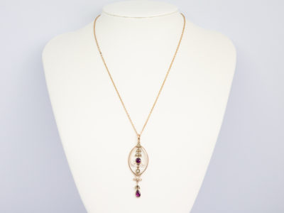 9 Karat rose gold pendant with garnet. c1910 Art Nouveau Lavaliere pendant with garnet and seed pearls on a fine 9 karat gold chain. Hallmarked 9ct on back of pendant and to the clasp. Pendant drop length 60mm and 20mm wide at widest area. Main photo of necklace displayed on a stand.
