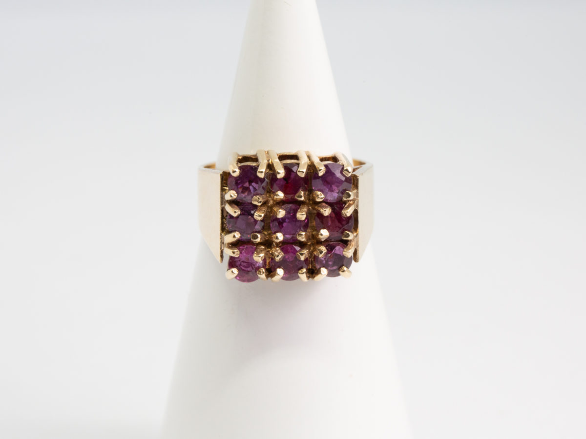 c1976 9 karat gold and ruby ring. Vintage ring in solid 9 karat gold with 9 round cut pink rubies set on a square setting. Ring size N / 6.75 Ring weight 5.4gms. Main photo of ring on a cone display stand with ring front to the centre of photo.