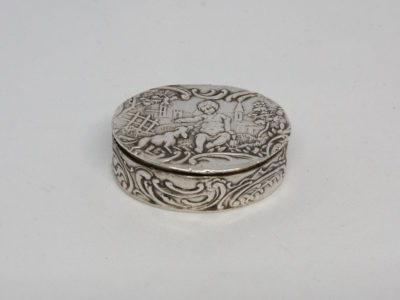 Antique 930 silver oval pill box. Lovely pill box with relief work decoration of a child with a dog in a rural setting. Full hallmark to the base with import mark c1900 Mueller and smaller hallmark to the inside rim of lid. Main photo of box with lid closed showing the relief work design to the top of lid and decoration to the side.