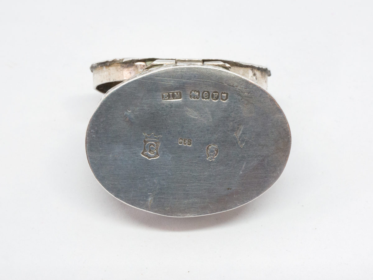 Antique 930 silver oval pill box. Lovely pill box with relief work decoration of a child with a dog in a rural setting. Full hallmark to the base with import mark c1900 Mueller and smaller hallmark to the inside rim of lid. Close up photo of hallmark on the base of box.