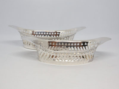 Pair of Edwardian bonbon dishes. 2 identical bonbon dishes with different assay offices and makers. Sheffield assay c1901 by Henry Aitken and London assay c1902 by Goldsmiths & Silversmiths Co. Ltd. Some minor signs of wear and a few minor dings consistent with the antique status of the dishes. Each dish measures approximately 97mm by 52mm at the base 62mm by 70mm at the top. Height at middle 30mm and at raised ends 43mm. Main photo of both bonbon dishes with one laid in front of other both seen lengthways