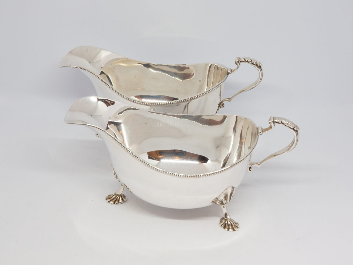 Pair of sterling silver sauce boats. Lovely pair of solid sterling silver sauce boats with claw feet and beading detail. Edinburgh assay and made by Hamilton & Inches c1936. Both in very good condition with only minor signs of wear. Each measures approximately 175mm long at longest (tip of spout to handle), 84mm at widest and 82mm tall at tallest (at handle top) Photo of both sauce boats shown lengthways with one in front of other and from a slight height.