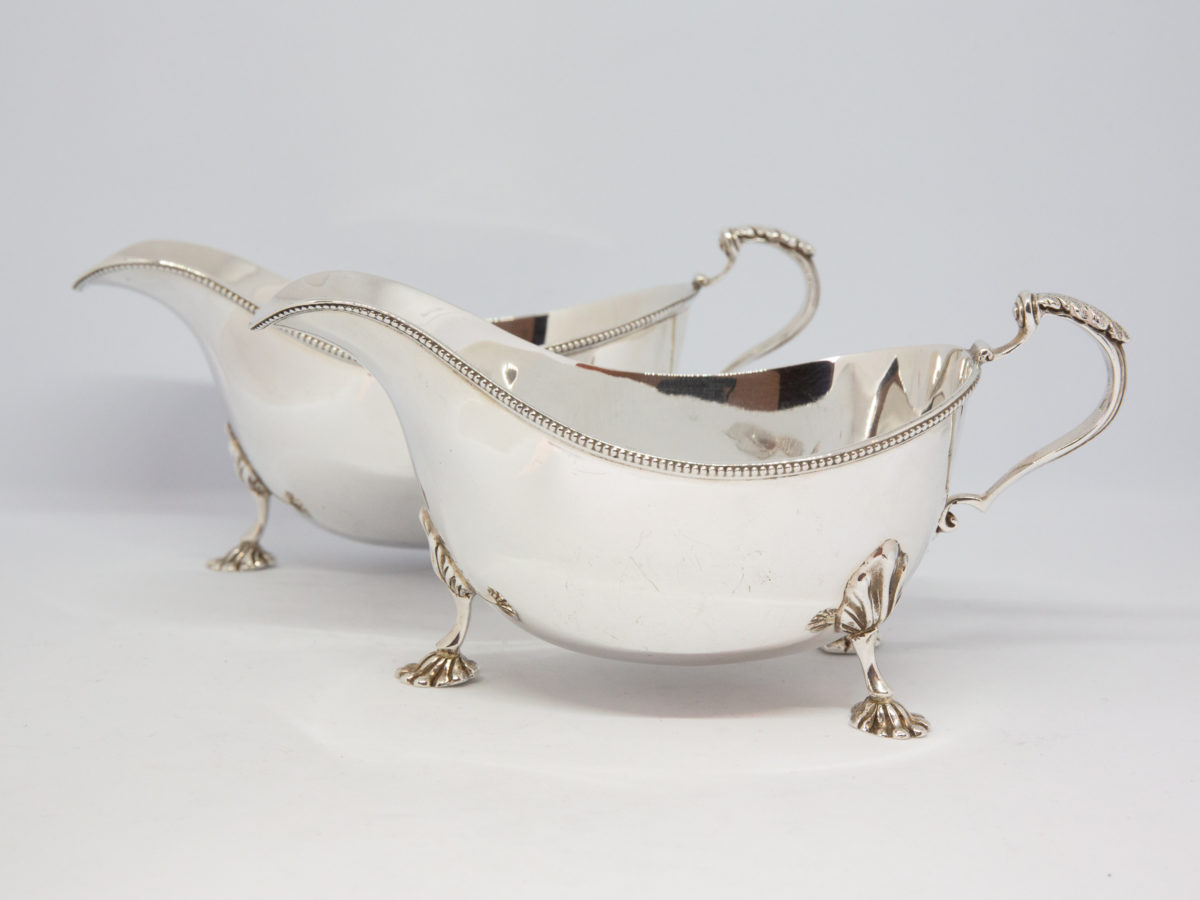 Pair of sterling silver sauce boats. Lovely pair of solid sterling silver sauce boats with claw feet and beading detail. Edinburgh assay and made by Hamilton & Inches c1936. Both in very good condition with only minor signs of wear. Each measures approximately 175mm long at longest (tip of spout to handle), 84mm at widest and 82mm tall at tallest (at handle top) Main photo of both sauce boats seen with one in front of the other and lengthways.