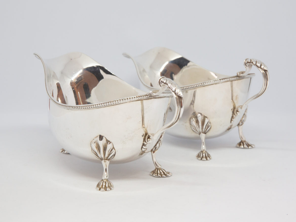 Pair of sterling silver sauce boats. Lovely pair of solid sterling silver sauce boats with claw feet and beading detail. Edinburgh assay and made by Hamilton & Inches c1936. Both in very good condition with only minor signs of wear. Each measures approximately 175mm long at longest (tip of spout to handle), 84mm at widest and 82mm tall at tallest (at handle top). Photo of both sauce boats stood side by side with handle and 2 rear feet end taking prominence in the shot.