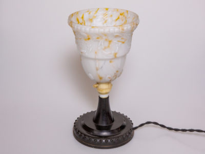 1930s Art Deco lamp with Bakelite base. Small up-lighting lamp with marble effect glass shade in cream with caramel coloured flecks on a moulded brown/black Bakelite base. Base measures 128mm in diameter and top of lamp measures 132mm in diameter. Main photo of lamp seen unlit and from a slightly raised angle with wire flex to the right of photo.