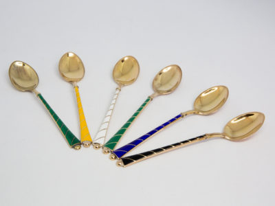 Set of 6 mid century coffee spoons. Lovely set of 6 gilt sterling silver and enamel coffee spoons by Egon Lauridsen of Denmark in original case. Each spoon with a different colour enamel to the handle. Hallmarked Ela Denmark Sterling 925S to the back. Each spoon measure approximately 93mm long and weighs 7.6gms. Main photo of spoons laid out in a fan like pattern with handles together in the foreground and spoon bowls fanned out.
