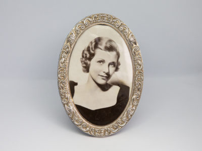 Modern oval silver photo frame. c2004 Birmingham assayed sterling silver photo frame made by WI Broadway & Co. Nice pattern work around the frame with birds. Photo area opening measures 138mm tall by 88mm at widest. Main photo of frame looing straight on.