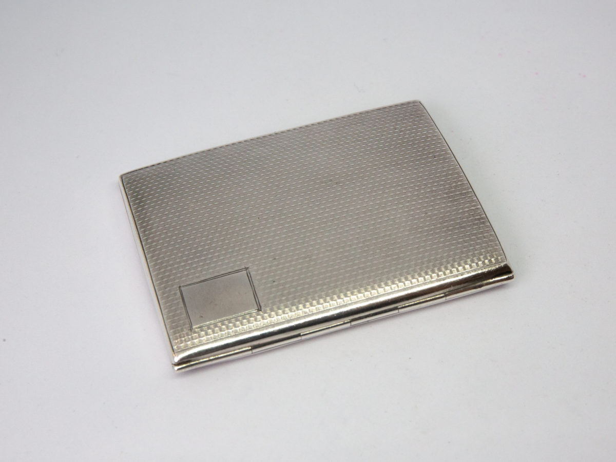 Small sterling silver cigarette case. c1929 Birmingham assayed sterling silver Art Deco cigarette case/business card holder. Lovely engine turned design to both sides with an empty cartouche to the lid for personalisation. Worn gilt interior with elastic intact. Hallmark to both inside covers and a lion passant on the opening lip. Photo of closed case seen at a diagonal angle to show the hinge area.