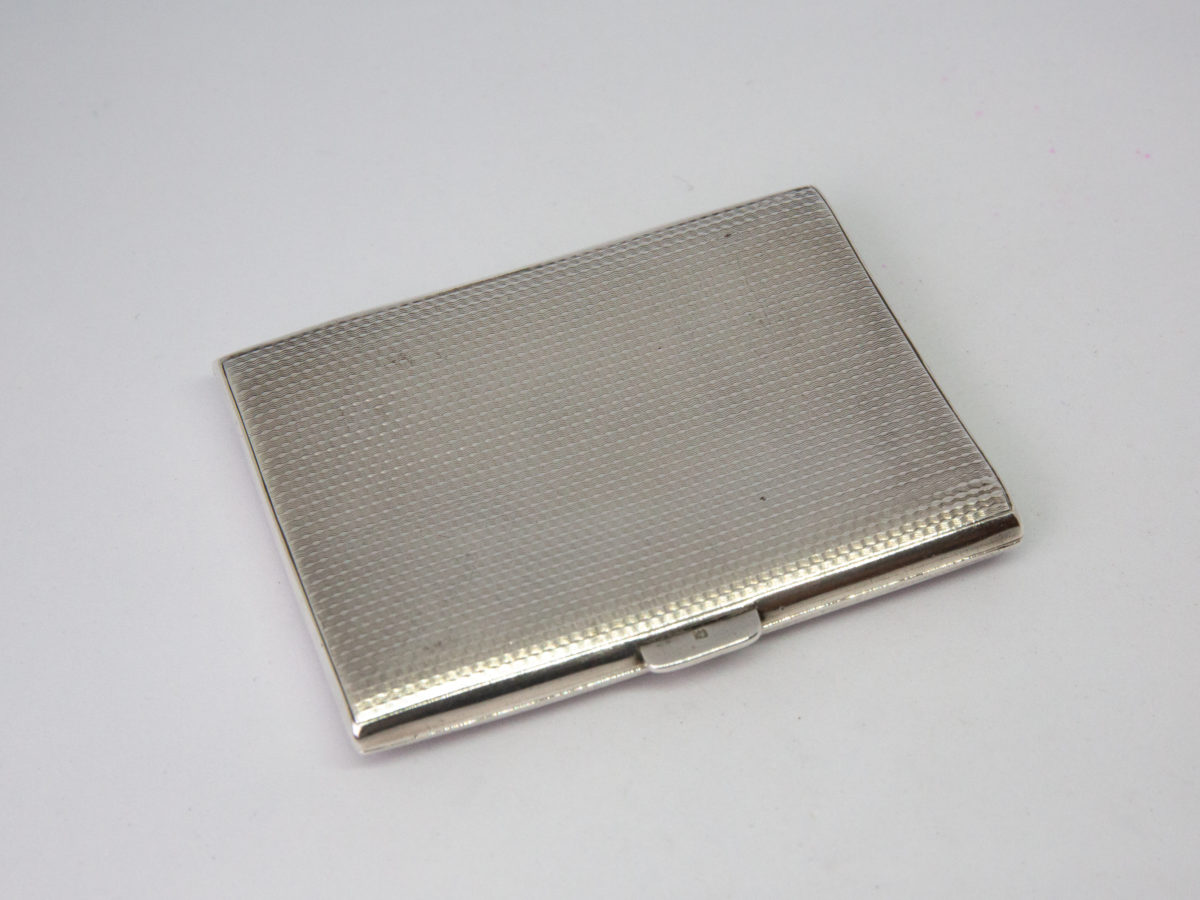 Small sterling silver cigarette case. c1929 Birmingham assayed sterling silver Art Deco cigarette case/business card holder. Lovely engine turned design to both sides with an empty cartouche to the lid for personalisation. Worn gilt interior with elastic intact. Hallmark to both inside covers and a lion passant on the opening lip. Photo showing the back of case with the lion passant hallmark just visible on the lip.