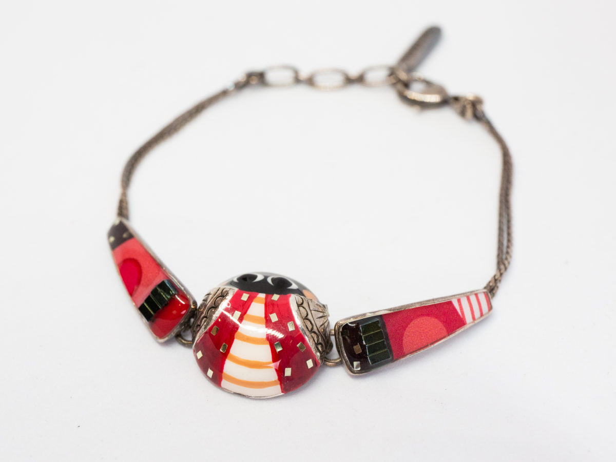 Modern metal & enamel ladybird bracelet. Fun and colourful ladybird bracelet in enamel set on white metal. Slightly adjustable from 160mm to185mm. Central section measures 17mm in diameter. Lovely gift item for children of all ages! Photo of bracelet with ladybird slight to the bottom left