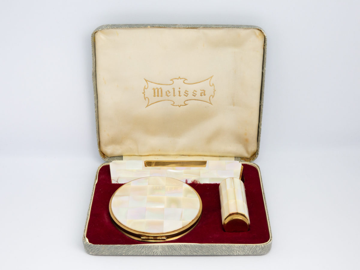Vintage cased Melissa vanity set. Nice cased set consisting of a cased comb, compact and lipstick case. Each piece in gilt metal with mother of pearl accent. All in excellent condition except for the comb case which has a small piece of MOP missing. Lovely complete vintage set. Comb case measures 117mm by 27mm.Compact measures 77mm in diameter. Lipstick case measures 60mm long, 22mm in diameter at top and 20mm in diameter at base. Main photo of all 3 pieces displayed in their slots inside the open case with makers name Melissa visible on the inside of lid.