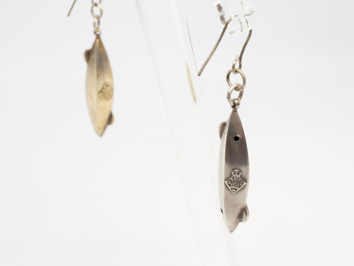 Victorian silver canoe earrings. Very unusual pair of canoe earrings with oar across the top of canoe. One canoe is silver coloured whilst other has slight golden hue and maybe gilded to distinguish 2 sides (Oxford V Cambridge perhaps?) Antique kitemark hallmark to the back of each canoe c1880. (This year being significant in that it is the only time in the history of the boat race that it was postponed for 2 days due to thick fog) Drop length approximately 45mm with canoe measuring approximately 30mm. Earrings weight 2.8gms. Box included. Close up photo of backs of both earrings showing the kitemark hallmark.