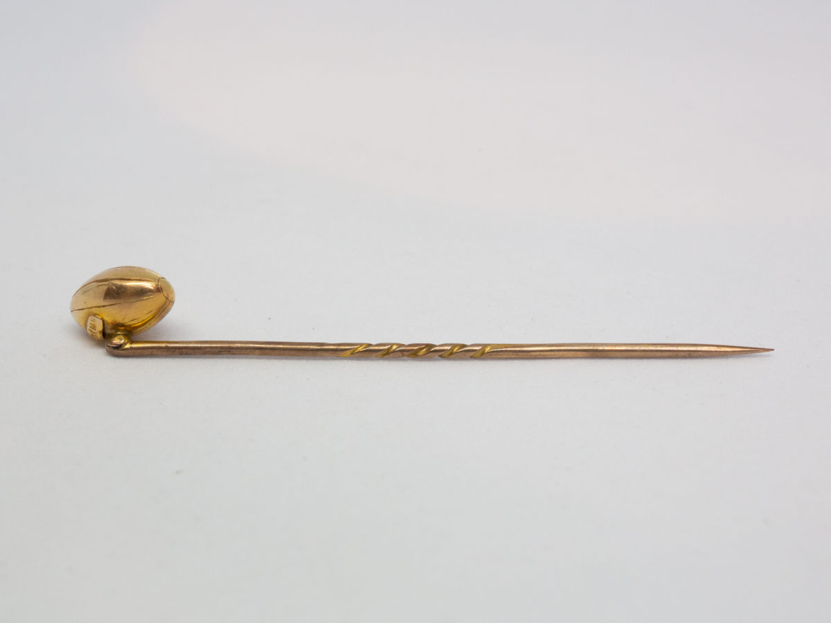Victorian 15 karat gold stick pin. Beautifully crafted rugby ball stick pin. Hallmarked 15ct to back of ball. Definitely one for the lover of rugby ! Measures approximately 60mm long and weighs 2.5gms. Rugby ball measures approximately 10mm long. Photo of stick pin on a flat surface with rugby ball to the left of picture and facing away from camera.