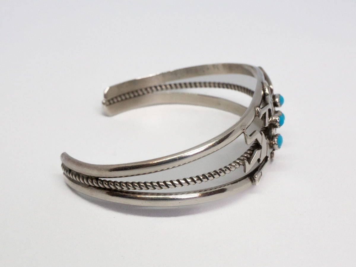 Vintage Navajo silver cuff bracelet. High quality cuff bracelet in sterling silver with Kokopelli characters decorated with Sleeping Beauty turquoise stones. Hallmarked sterling to the back and signed by the designer Ella Peter. Really lovely piece of Native American jewellery. Cuff opening measures 30mm but can be slightly manipulated. Photo of cuff bracelet from the side with bracelet front to the right of photo.