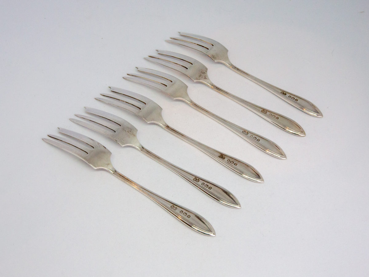Cased set of sterling silver cake forks. Nice set of 6 cake/dessert forks in original case. Each fork is hallmarked to the back of handle for Birmingham assay c1941. Made by William Suckling Ltd of Albion and Vyse Street. Each fork weighs 16.5gms and measures 128mm long. Photo of all 6 forks laid out with tine side face down and in the top left corner and handles in bottom right corner.