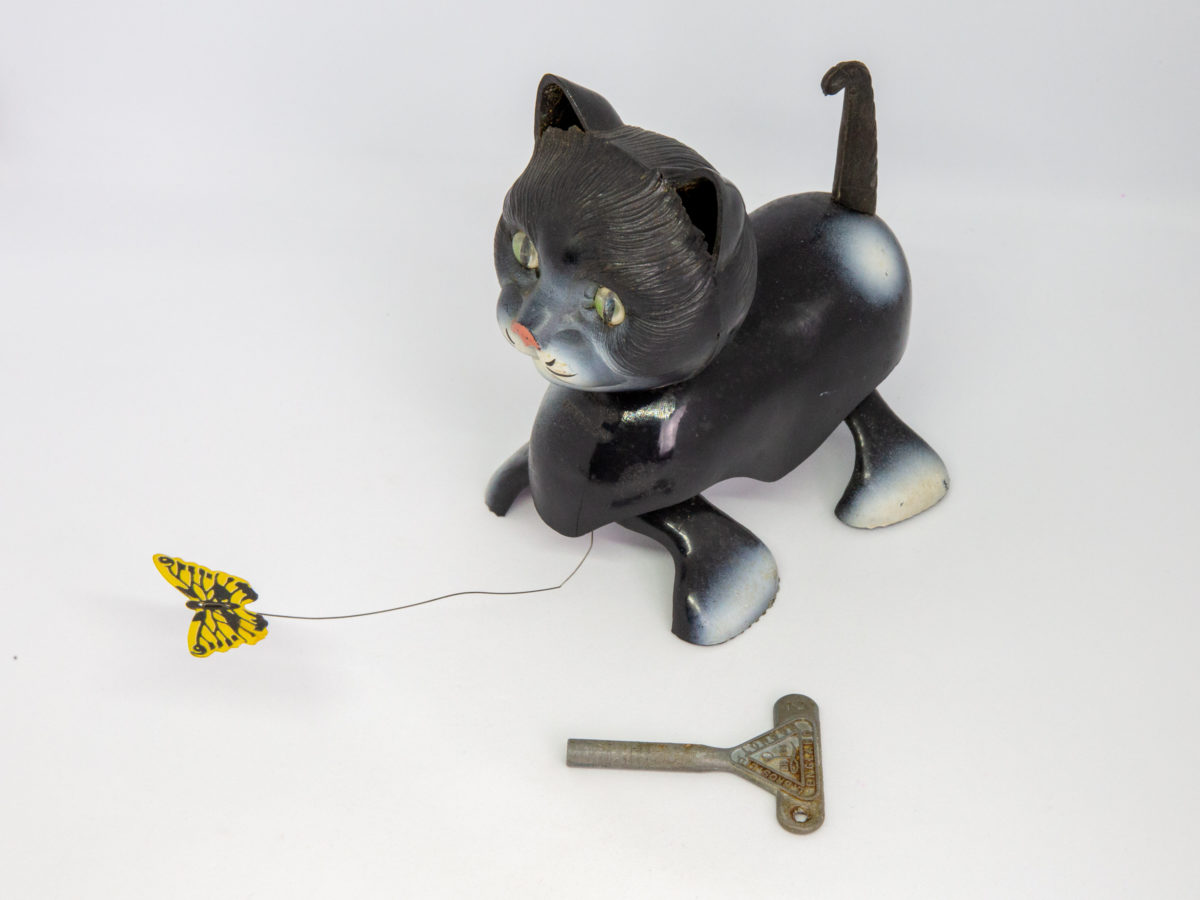 1950s Tri-Ang Minic clockwork cat. Fun novelty clockwork cat toy that chases a butterfly. Oddly realistic in detail. No original box or key. Key is included but not the original one. Cat measures approximately 100mm long, 107mm tall (at head) and 65mm wide. Main photo of cat appearing to be looking at butterfly with key in the foreground. Cat is facing bottom left of photo.