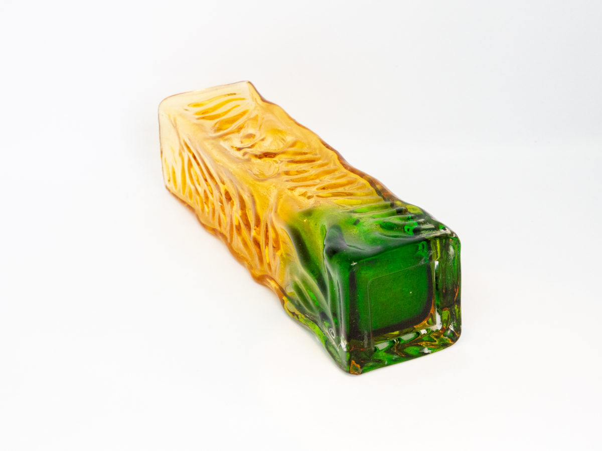 Whitefriars small rectangular vase. Small and sweet Whitefriars rectangular glass vase with a vibrant green base and yellow top. Measures 47mm square at base. Photo of vase on its side and seen with the vibrant green base in the foreground.