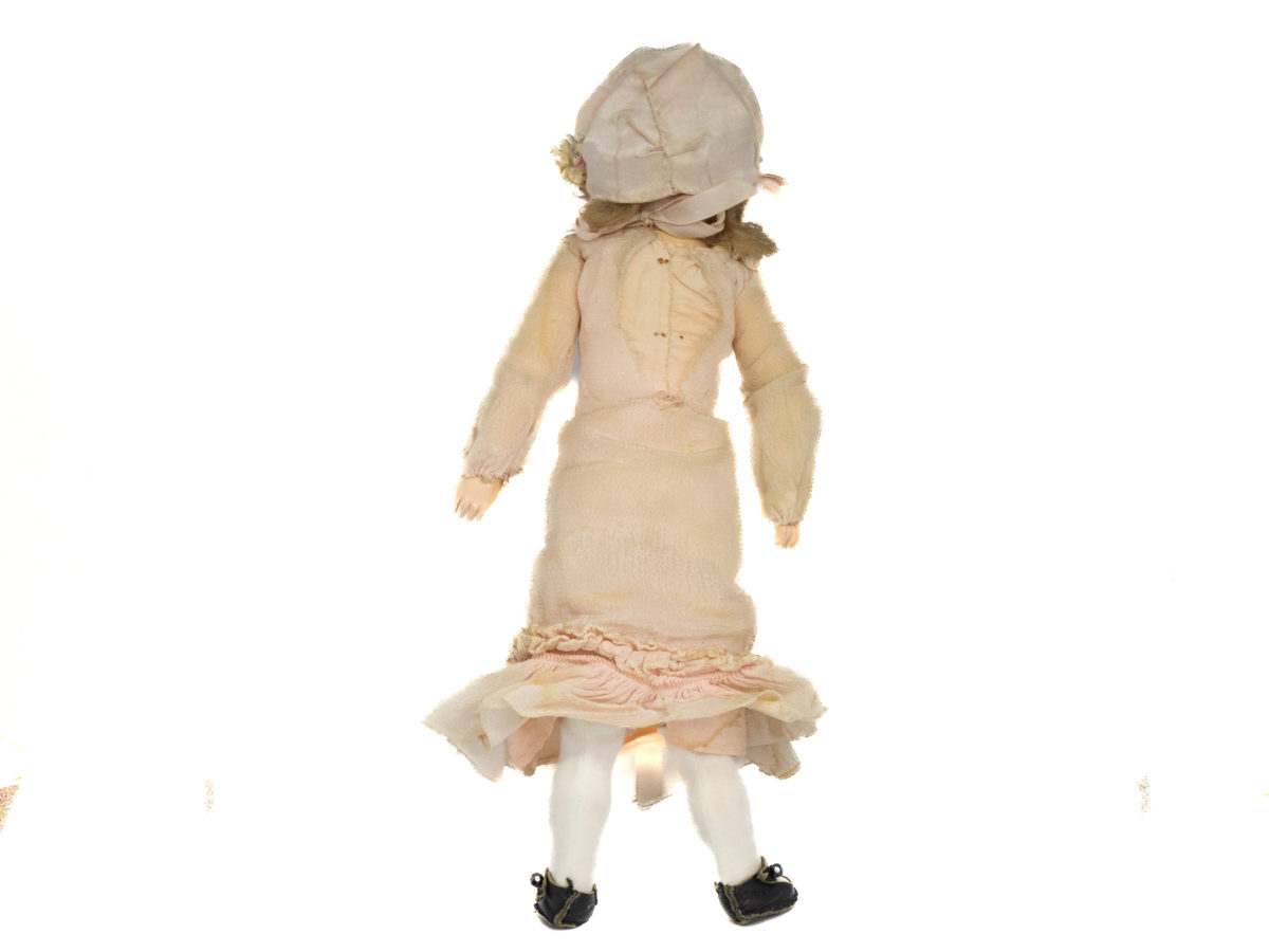 Antique Armand Marseille doll number 7. Petite bisque head doll in pale peach colour attire with incredibly realistic hand-painted features. Some wear to the clothing but otherwise in fabulous condition for a doll c1915. Measures approximately 335mm tall, 75mm wide at the hips and 55mm deep. Photo of doll in an upright position and seen from the back.
