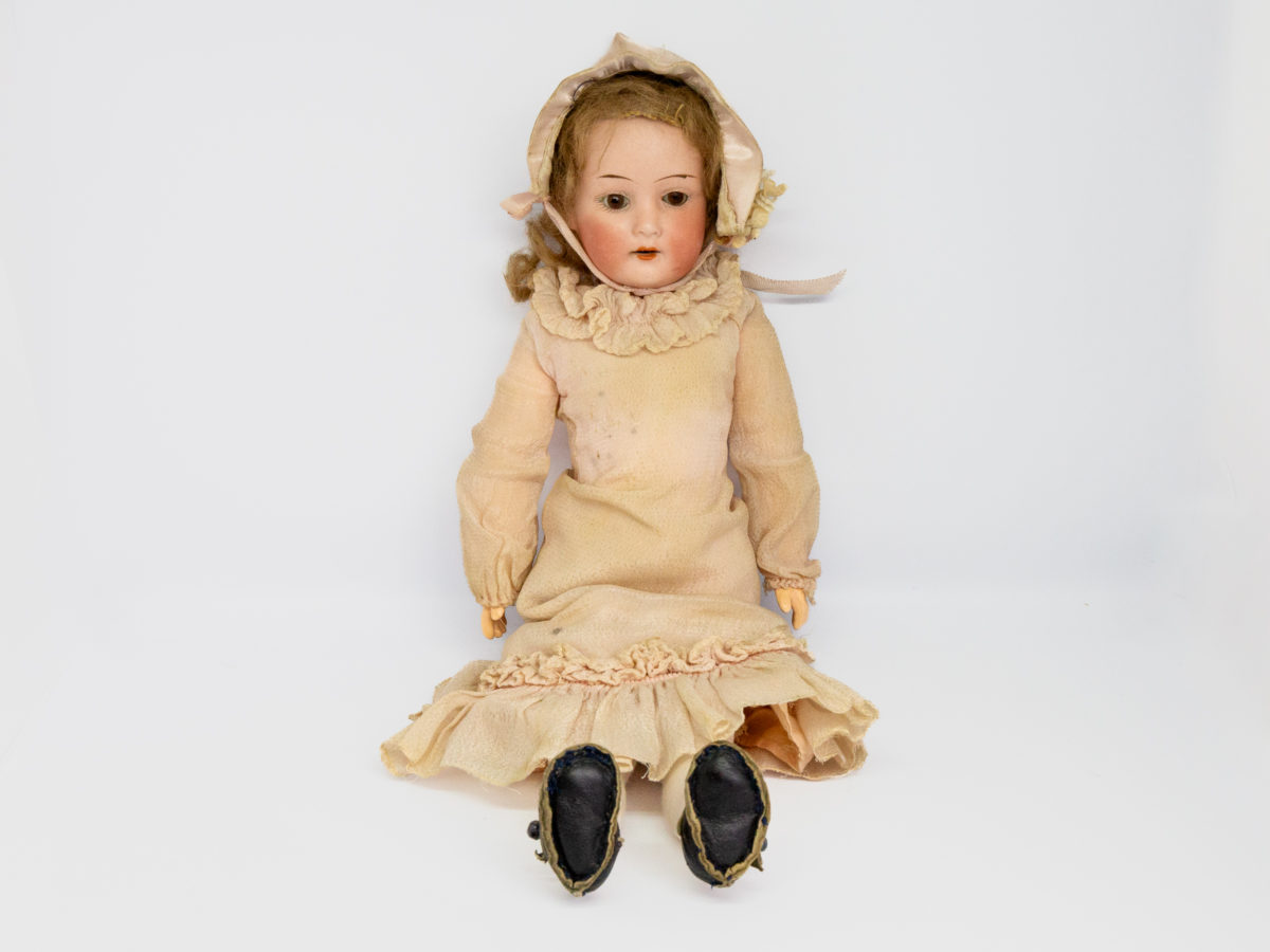 Antique Armand Marseille doll number 7. Petite bisque head doll in pale peach colour attire with incredibly realistic hand-painted features. Some wear to the clothing but otherwise in fabulous condition for a doll c1915. Measures approximately 335mm tall, 75mm wide at the hips and 55mm deep. Photo of doll seated and shown from the front.