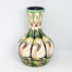 Moorcroft 'lily come home' vase. Modern Moorcroft vase designed by Emma Bossons in a repeated design pattern of white lily flowers. Signed and dated to the base. Measures 80mm in diameter at base, 120mm in diameter at most bulbous part and 57mm in diameter across the top. Main photo of vase shown from a near eye level angle .